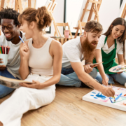 Group of people smiling happy drawing sitting on the floor at art studio.