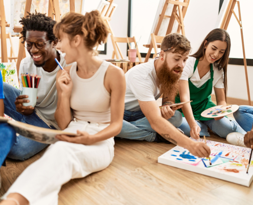 Group of people smiling happy drawing sitting on the floor at art studio.