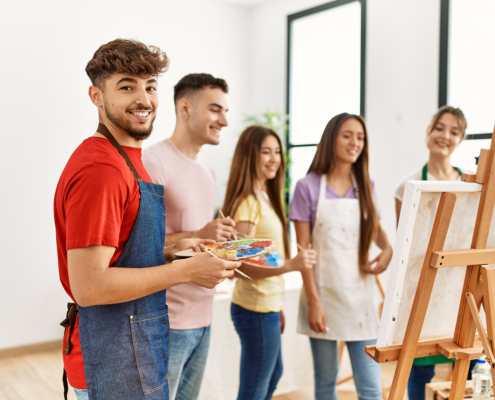 Group of people smiling happy drawing on canvas standing at art studio.